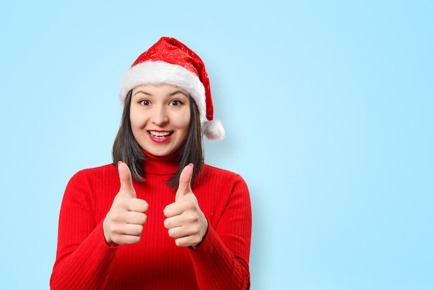 Frau in der roten Strickjacke und im Weihnachtshut auf blauem Hintergrund