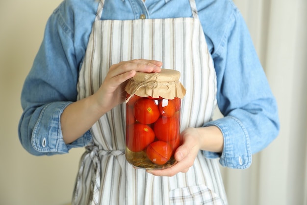 Frau in der Schürze halten Glas mit eingelegten Tomaten