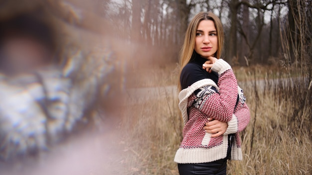 Frau in der schwarzen Hose und im warmen Pullover, die auf dem Gebiet der getrockneten Ährchen stehen