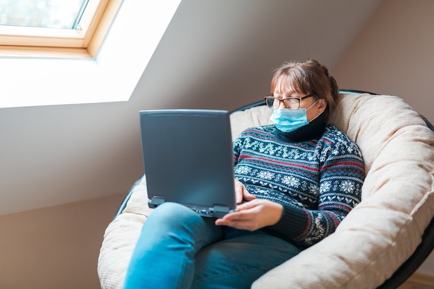 Frau in der Selbstisolierung, die Fernarbeit auf einem Laptop tut