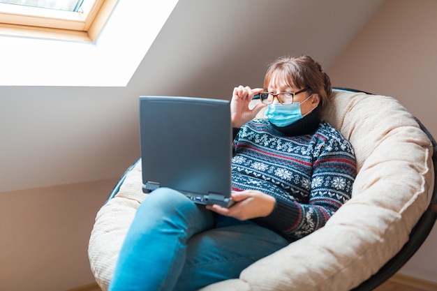 Frau in der Selbstisolierung, die Fernarbeit auf einem Laptop tut