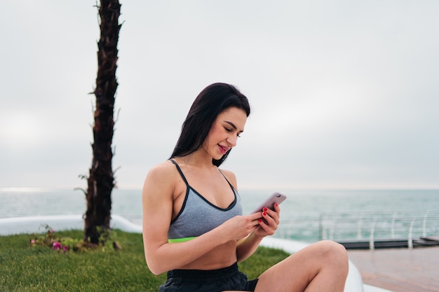 Frau in der Sportbekleidung, die ein Smartphone hält