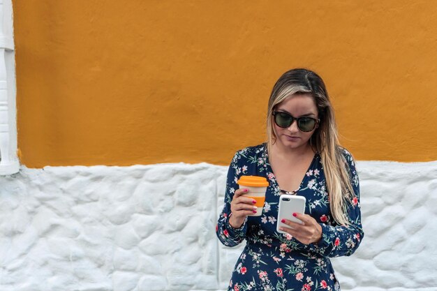 Frau in der Stadt, die das Telefon benutzt und Kaffee trinkt