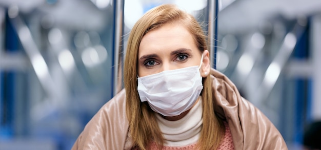 Frau in der U-Bahnstation, die schützende chirurgische Hygienemaske im Gesicht trägt, verhindert das Risiko des Coronavirus