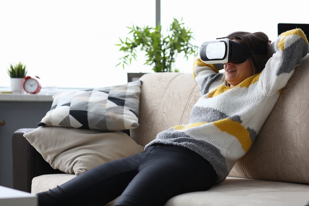 Frau in der virtuellen Brille, die auf der Couch sitzt