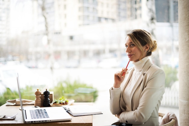 Frau in der weißen Reihe, die an Laptop am Business-Lunch arbeitet