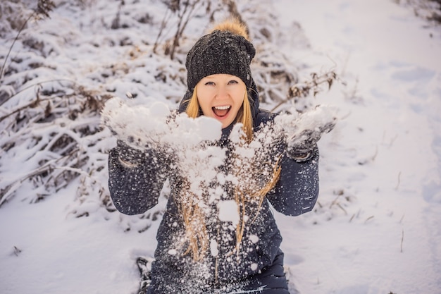 Frau in der Winterkleidung, die mit Schnee spielt