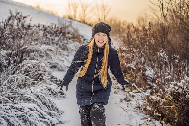 Frau in der Winterkleidung, die mit Schnee spielt