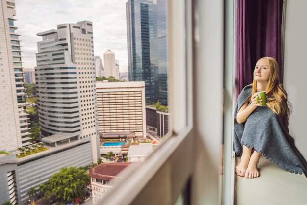 Frau in eine Decke gehüllt und mit Blick auf die Großstadt