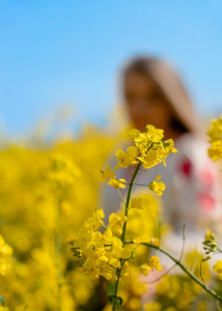 Frau in einem bestickten Hemd in einem Rapsfeld gegen den blauen Himmel am Frühlingstag