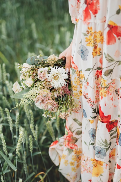 Frau in einem Blumenkleid mit einem Blumenstrauß