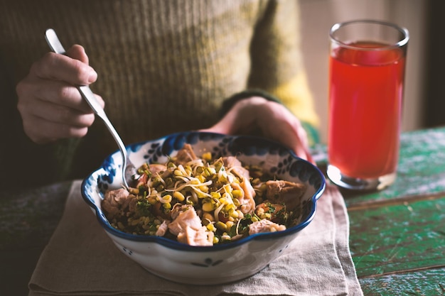 Frau in einem grünen Pullover, die einen Salat mit Hähnchen und Bohnen isst