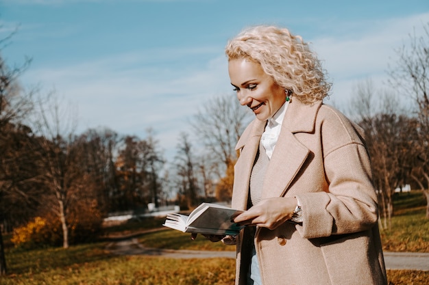 Frau in einem Herbstmantel hält ein Buch