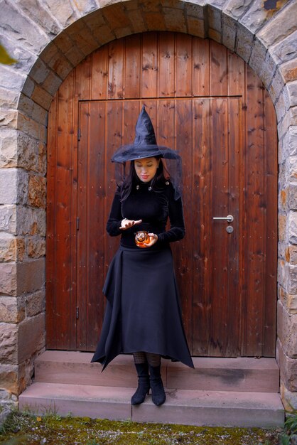 Frau in einem Hexenkostüm in einem Herbstwald oder Schloss Halloween