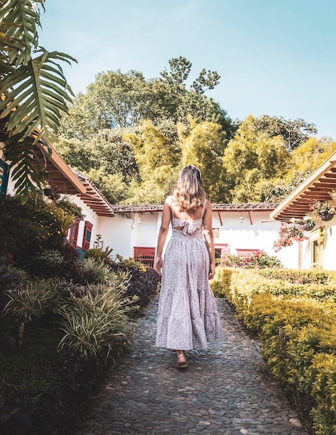 Frau in einem Kleid, die durch den Garten in einem Bauerndorf geht