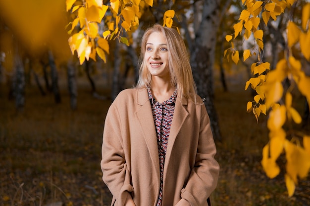 Frau in einem langen Mantel im Herbstwald