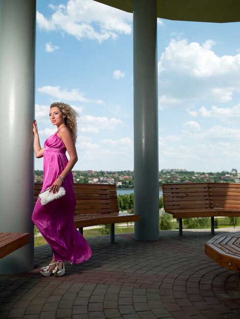 frau in einem rosa kleid steht in der nähe der säule