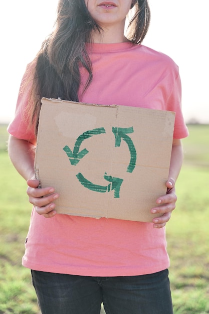 Foto frau in einem rosa t-shirt mit einem pappschild mit recycling-symbol