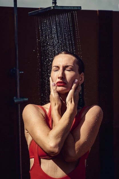 Frau in einem roten Badeanzug, der Dusche im Freien hat