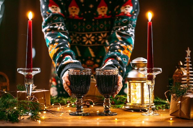 Frau in einem Weihnachtspullover, der Becher des Glitzernweins hält