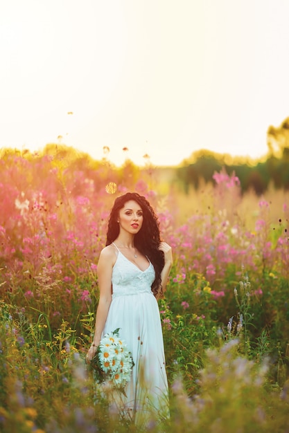 Frau in einem weißen Kleid, das in einem Feld aufwirft