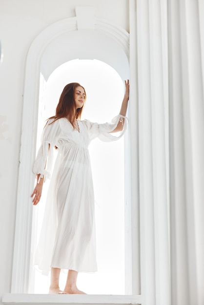 Frau in einem weißen Kleid in der Öffnung in Form eines Bogens posiert Hochqualitätsfoto