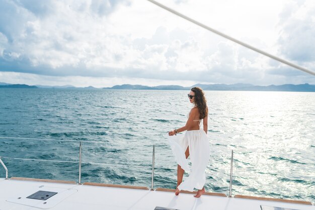 Frau in einem weißen Rock, der auf einer Yacht steht