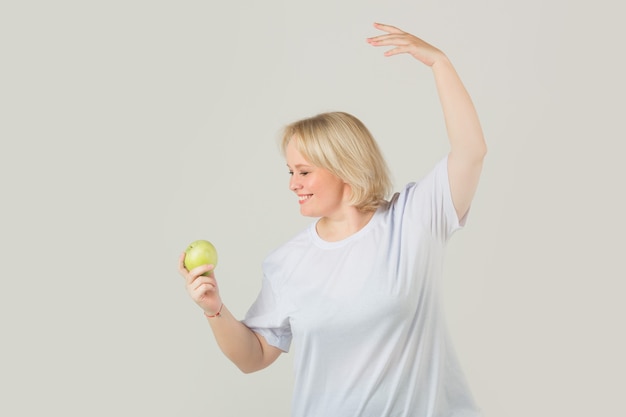 Frau in einem weißen T-Shirt mit einem grünen Apfel