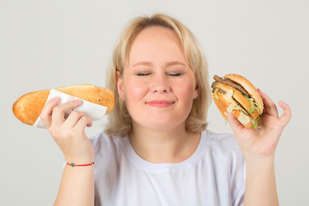 Frau in einem weißen T-Shirt mit Hamburger und Sandwich