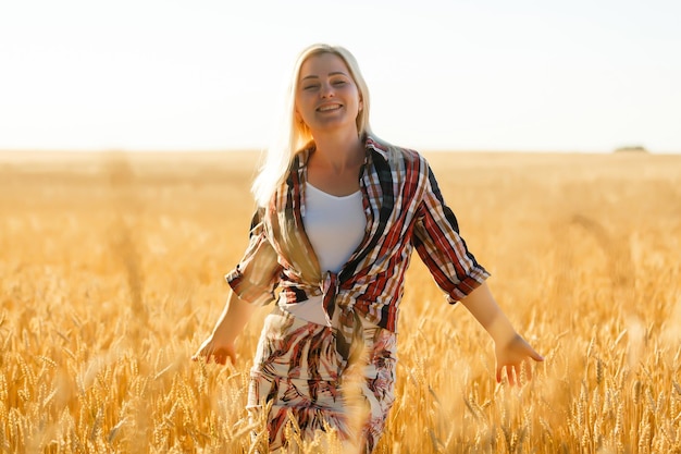 Frau in einem Weizenfeld vor dem Hintergrund der untergehenden Sonne