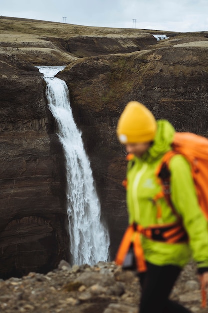 Frau in einer grünen Jacke am Wasserfall Haifoss, Island