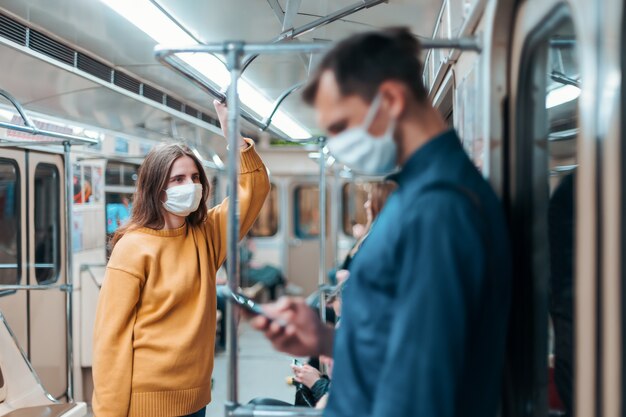 Frau in einer Schutzmaske, die in einem U-Bahnwagen steht