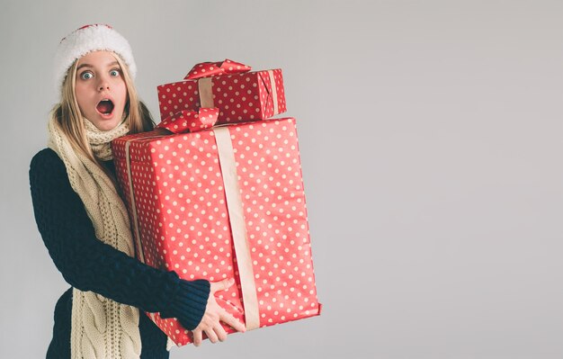 Frau in einer Weihnachtsmütze, die Geschenke hält