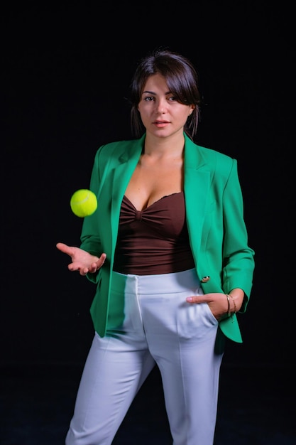 Frau in grüner Jacke mit Tennisball auf schwarzem Hintergrund