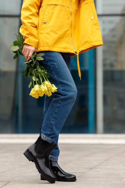 Frau in Gummistiefeln mit gelben Blumen Nahaufnahme