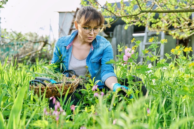 Frau in Handschuhen mit Schaufel Jäten Frühlingsblumenbeet von Unkraut