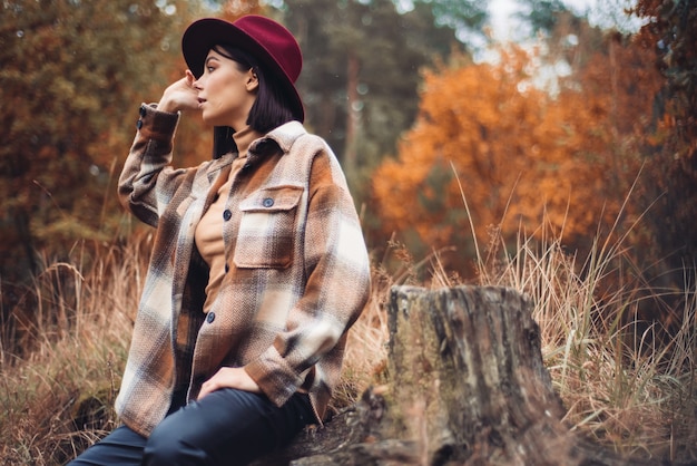 Frau in Hut und Mantel im Wald