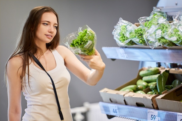 Frau in ihrem s wählt Salat im Supermarkt