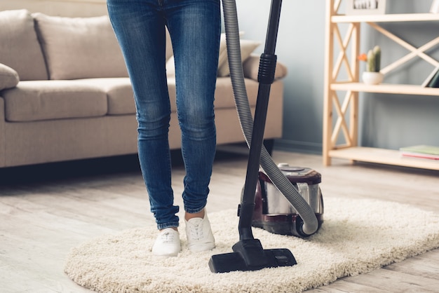 Frau in Jeans mit einem Staubsauger