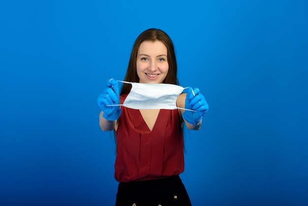 Frau in medizinischer Schutzmaske und blauen Handschuhen auf blauem Hintergrund.