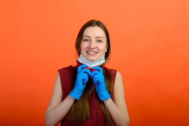 Frau in medizinischer Schutzmaske und blauen Handschuhen auf rotem Hintergrund.