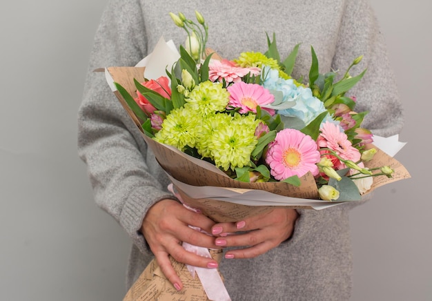 Frau in Pullover und Jeans mit schönem Blumenstrauß übergibt Muttertagskonzept zum Valentinstag