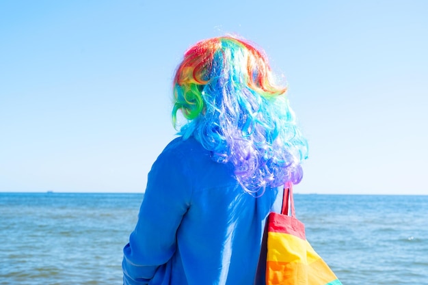 Frau in regenbogenfarbener Perücke über Sommerstrandhintergrund