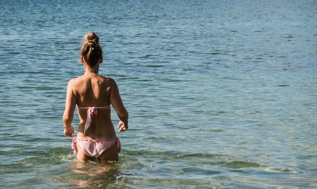 Frau in rosa Bikini ging aus einem See ins Wasser