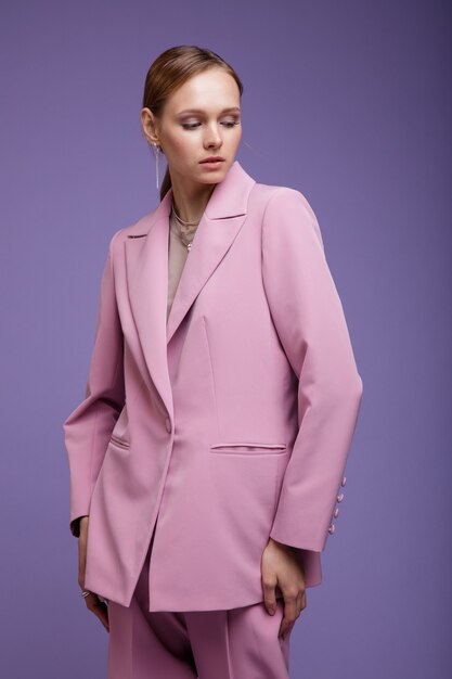 Frau in rosa übergroßer Anzugjacke auf lila lavendelfarbenem Hintergrund Studio Shot Portrait