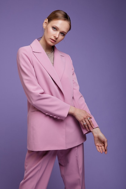 Frau in rosa übergroßer Anzugjacke auf lila lavendelfarbenem Hintergrund Studio Shot Portrait