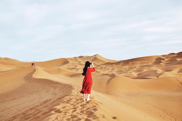 Foto frau in rotem kleid fotografiert in der wüste