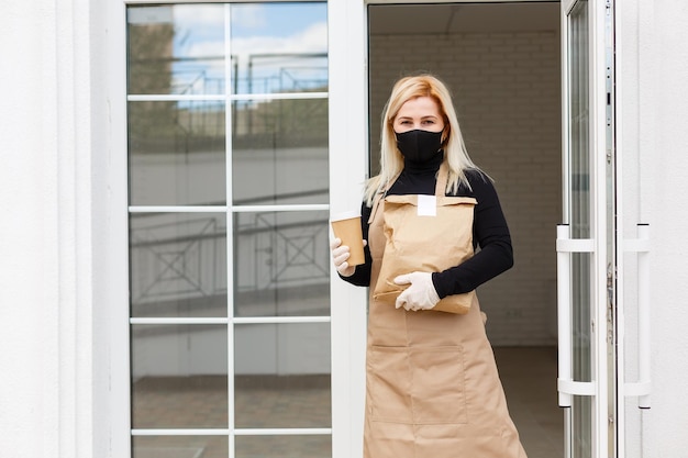 Frau in schürzenverpackungsprodukten in papiertüten zum verkauf in der werkstatt. konzept für kleine unternehmen.