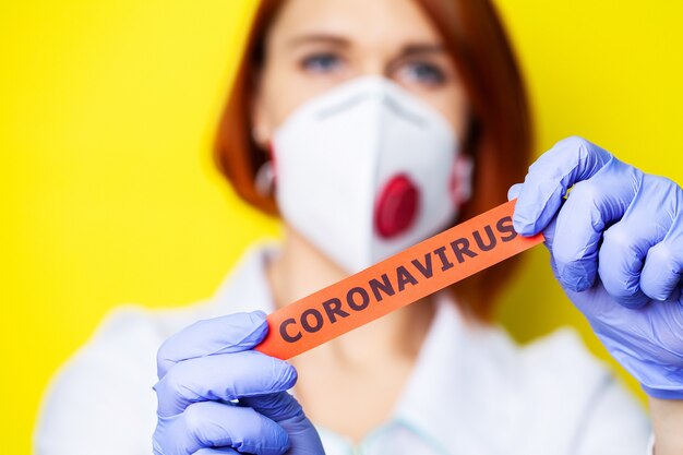 Frau in Schutzhandschuhen, die Inschrift Coronavirus halten.