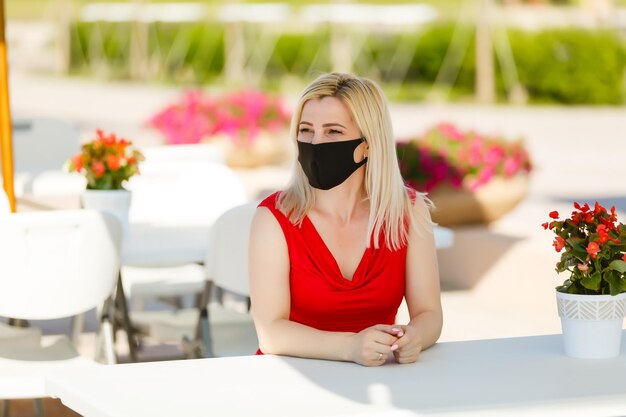 Frau in Schutzmaske auf der Sommerterrasse